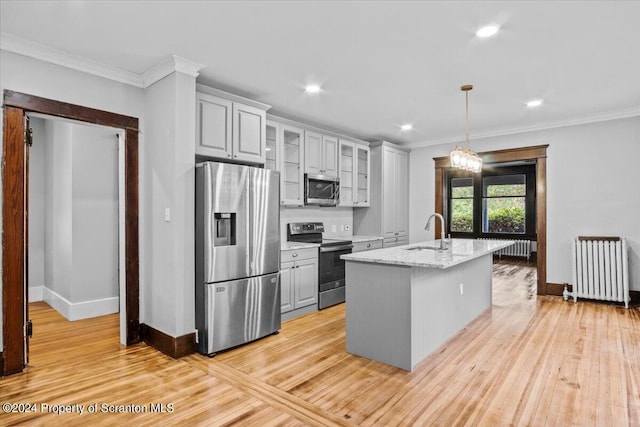 kitchen with radiator, light stone countertops, sink, stainless steel appliances, and a center island with sink