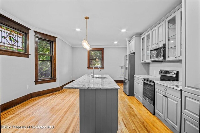 kitchen with gray cabinetry, a kitchen island with sink, sink, ornamental molding, and appliances with stainless steel finishes