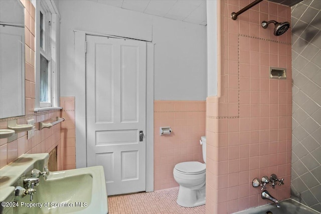 full bathroom with tile patterned floors, sink, tiled shower / bath combo, toilet, and tile walls