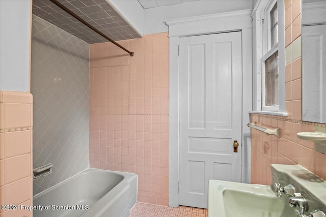 bathroom featuring tiled shower / bath combo, sink, and tile walls