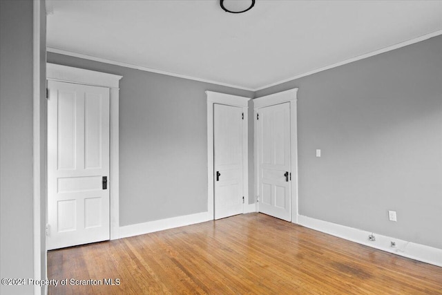 unfurnished bedroom with wood-type flooring and ornamental molding