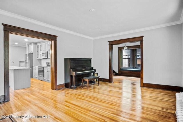 living room featuring light wood-type flooring, ornamental molding, and sink