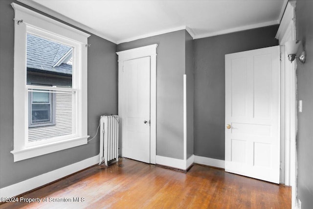 unfurnished bedroom featuring radiator heating unit, wood-type flooring, and ornamental molding