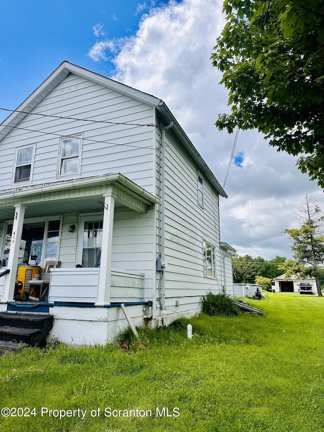 view of side of property with covered porch and a yard