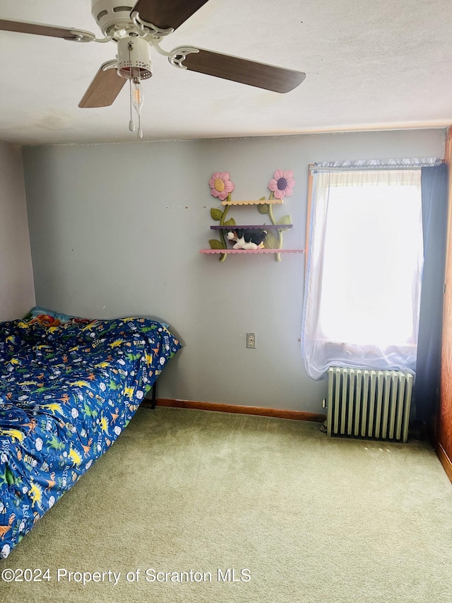 carpeted bedroom with ceiling fan and radiator heating unit