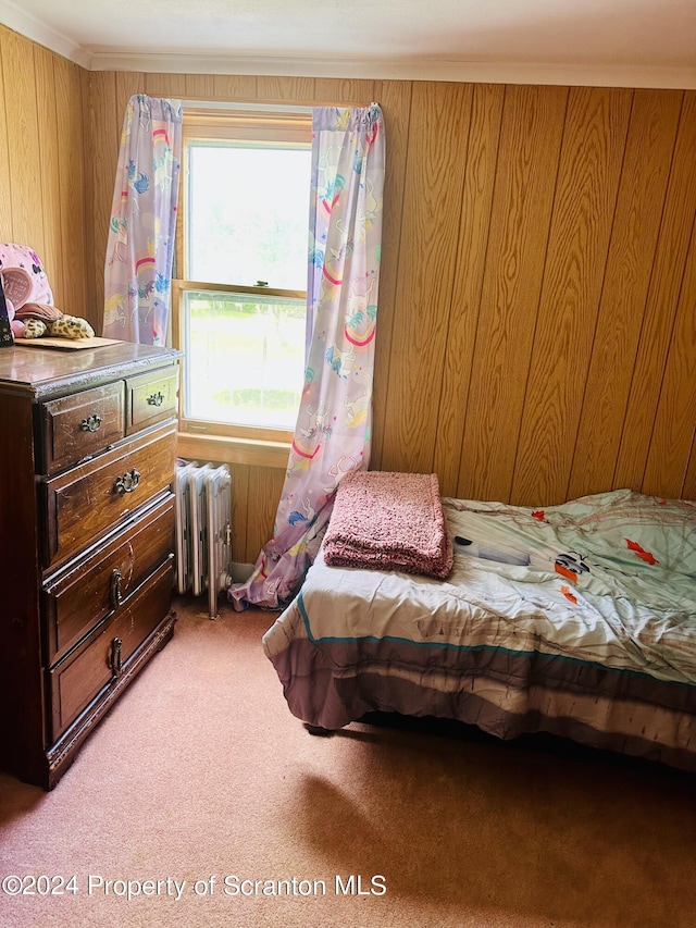 carpeted bedroom featuring radiator, crown molding, and wood walls