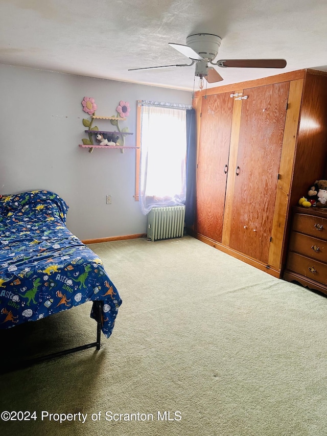 carpeted bedroom featuring ceiling fan and radiator heating unit