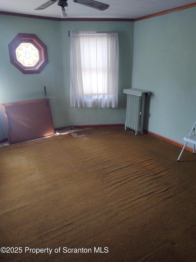 carpeted spare room with radiator, ceiling fan, ornamental molding, and baseboards