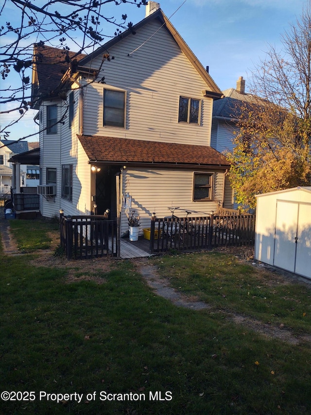 rear view of property featuring an outbuilding, a yard, a wooden deck, and a storage shed