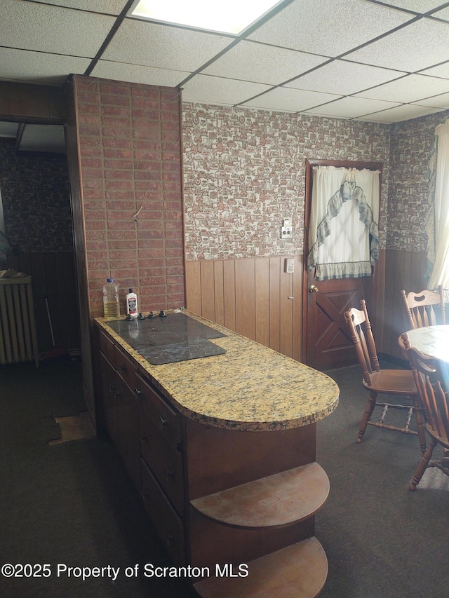 kitchen with radiator, a drop ceiling, and dark carpet