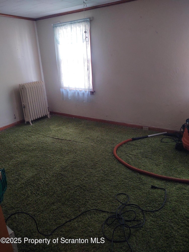 carpeted empty room featuring radiator heating unit, ornamental molding, and baseboards