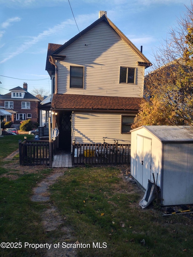 rear view of property featuring a shed, a lawn, and an outbuilding