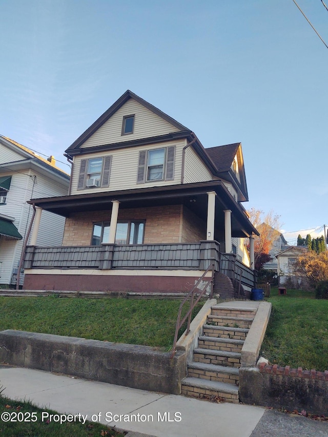 view of front facade featuring stairs, a front lawn, and a porch