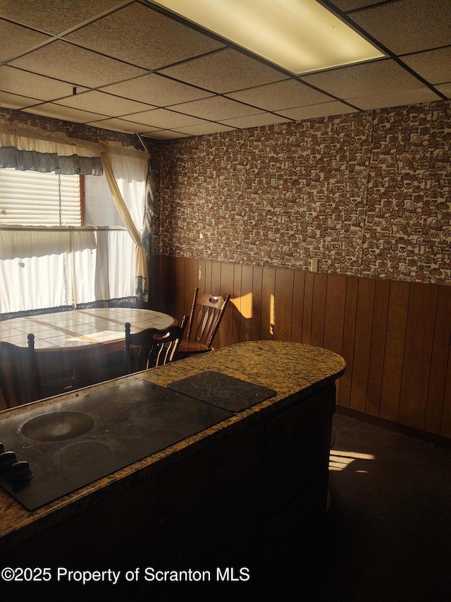 interior space with a paneled ceiling and black electric stovetop