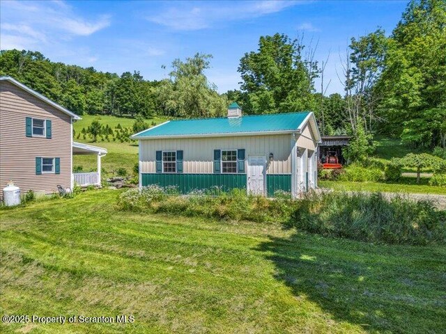 1715 Booth Rd, Hallstead, PA 18822 - view of front of property featuring a chimney, a front lawn, an outdoor structure, a metal roof, and board and batten siding