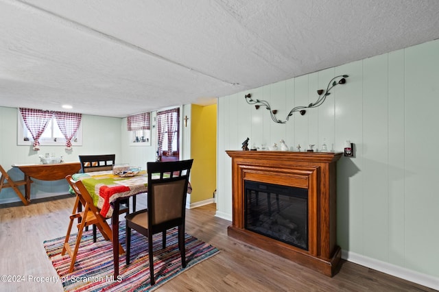 dining space featuring wood-type flooring and a textured ceiling