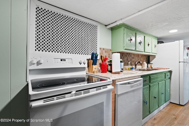 kitchen with sink, tasteful backsplash, green cabinets, a textured ceiling, and white appliances