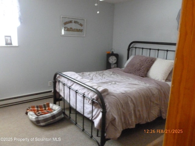 bedroom with a baseboard heating unit and carpet flooring