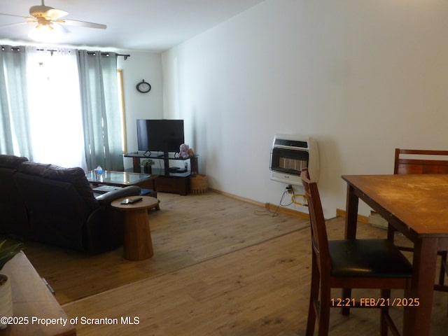 living room with ceiling fan, baseboards, wood finished floors, and heating unit