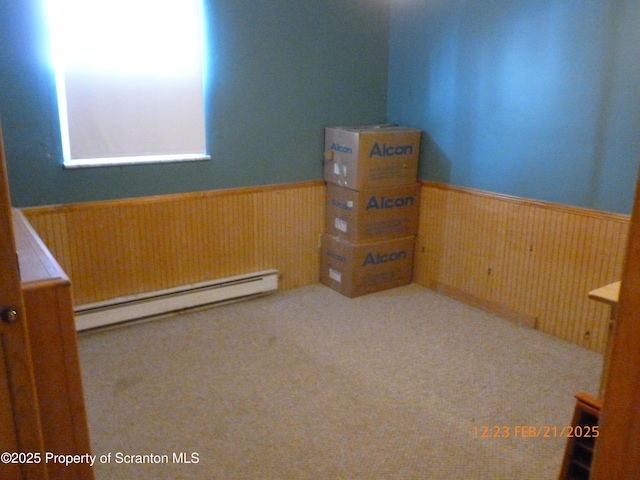 spare room with a wainscoted wall, a baseboard radiator, and wooden walls