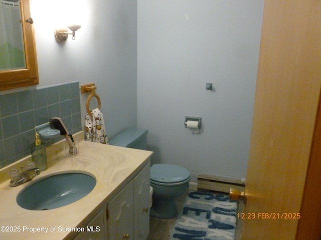 bathroom with tasteful backsplash, a baseboard radiator, vanity, and toilet