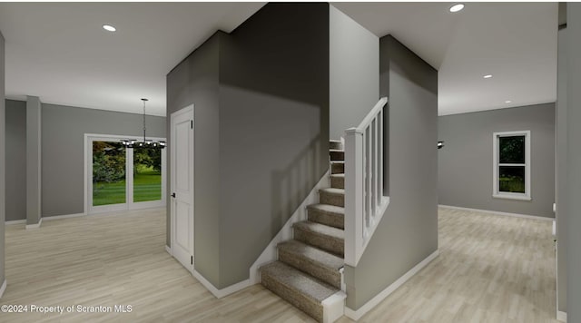 staircase with hardwood / wood-style floors and a notable chandelier