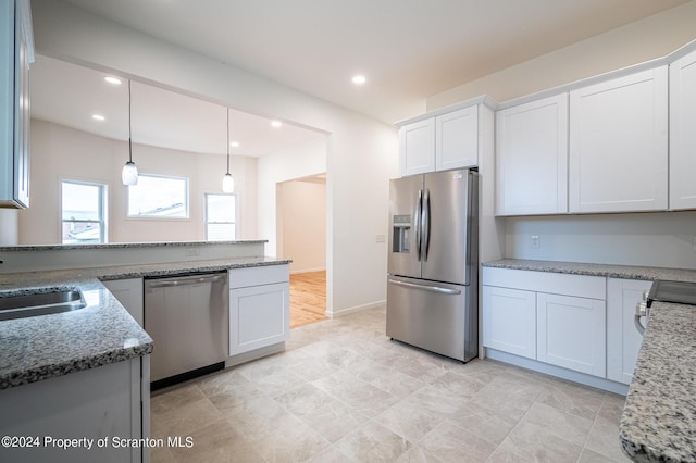 kitchen with stone countertops, white cabinetry, and stainless steel appliances