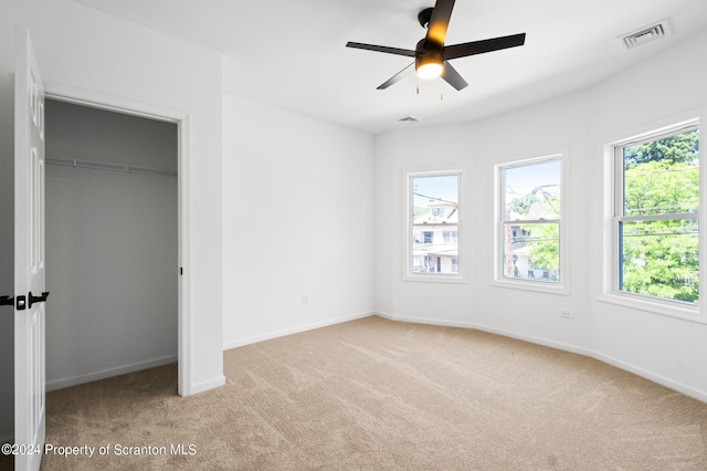 unfurnished bedroom with light carpet, a closet, and ceiling fan