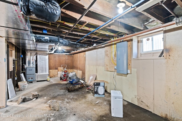 basement featuring electric panel and heating unit