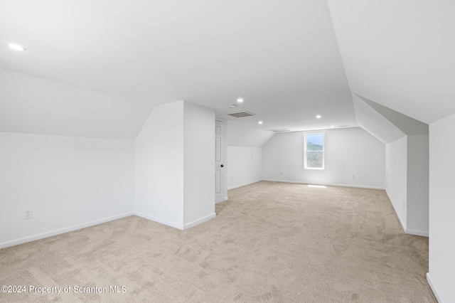 bonus room with light carpet and vaulted ceiling