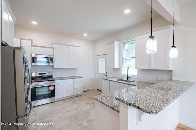 kitchen with kitchen peninsula, appliances with stainless steel finishes, sink, decorative light fixtures, and white cabinets