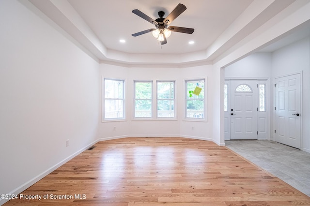 foyer with ceiling fan, light hardwood / wood-style floors, and a raised ceiling