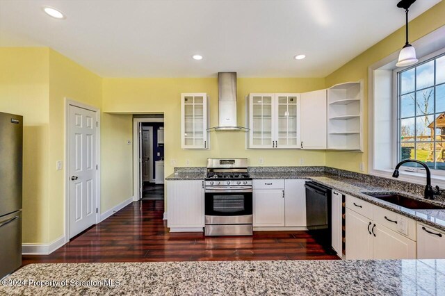 kitchen featuring white cabinetry, sink, wall chimney exhaust hood, stainless steel appliances, and decorative light fixtures