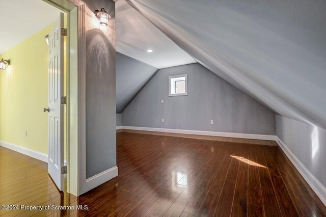 bonus room with dark wood-type flooring and vaulted ceiling