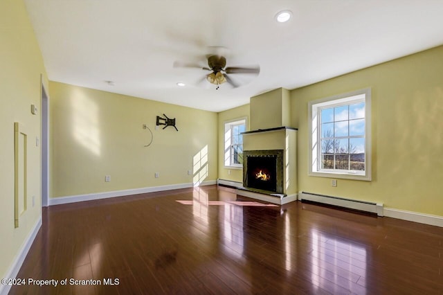 unfurnished living room featuring ceiling fan, dark hardwood / wood-style flooring, and a baseboard heating unit