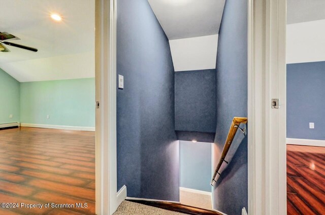 stairway with ceiling fan, a baseboard radiator, and vaulted ceiling