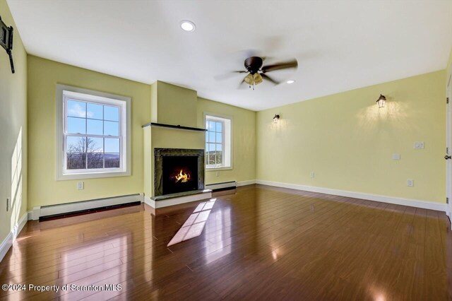 unfurnished living room featuring a baseboard radiator, ceiling fan, and a healthy amount of sunlight