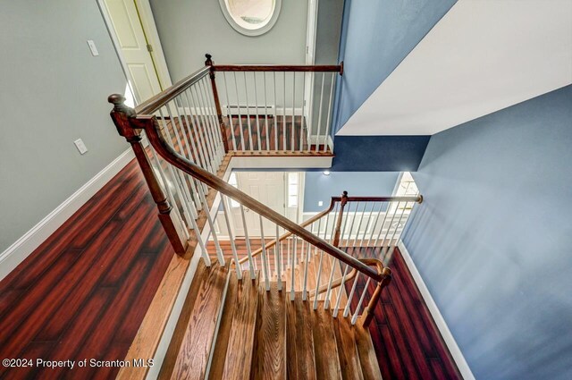 stairs featuring wood-type flooring and a baseboard heating unit