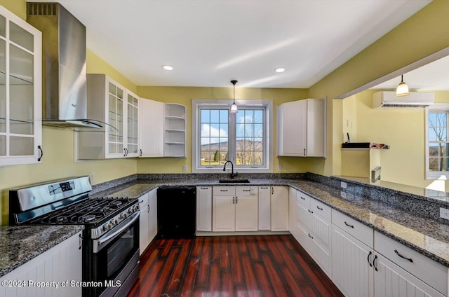 kitchen featuring dishwasher, stainless steel gas range oven, white cabinets, wall chimney range hood, and decorative light fixtures