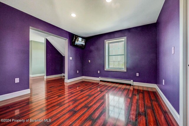 unfurnished room featuring wood-type flooring and baseboard heating