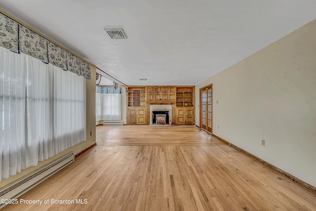 512 Thomas Dr, Dunmore, PA 18512 - unfurnished living room with a baseboard heating unit, built in shelves, a fireplace with raised hearth, a baseboard radiator, and light wood-type flooring