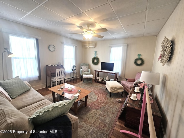 living room featuring dark wood-type flooring, a paneled ceiling, a wall mounted AC, and ceiling fan