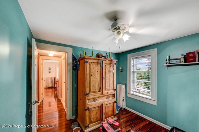 bedroom featuring ceiling fan, radiator heating unit, and dark wood-type flooring