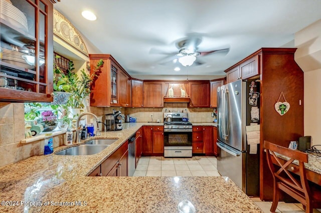 kitchen with sink, tasteful backsplash, light stone counters, light tile patterned floors, and appliances with stainless steel finishes