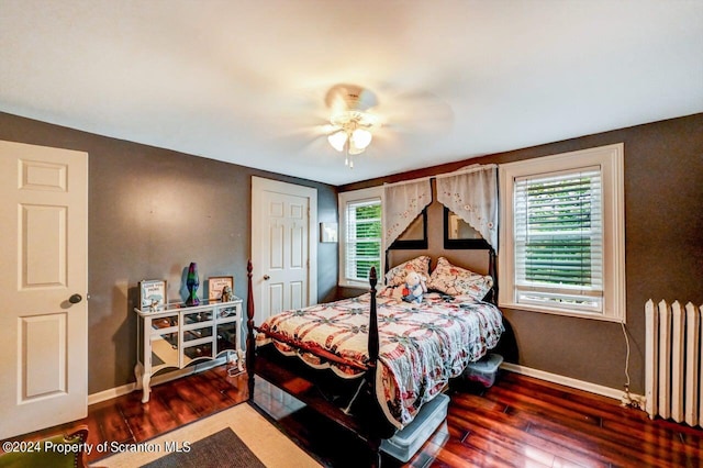 bedroom with multiple windows, radiator, ceiling fan, and dark wood-type flooring