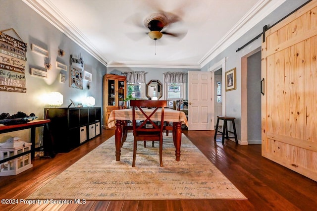 dining room featuring ceiling fan, a barn door, crown molding, and dark wood-type flooring