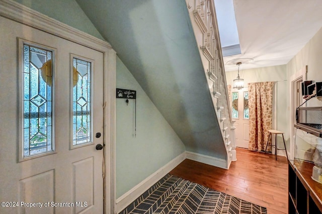 entryway with wood-type flooring, a wealth of natural light, and a notable chandelier