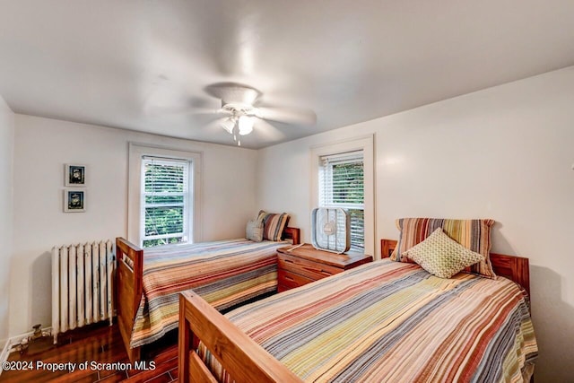 bedroom with multiple windows, radiator heating unit, dark hardwood / wood-style floors, and ceiling fan