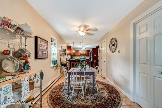 tiled dining space with ceiling fan and a baseboard radiator