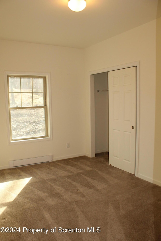 unfurnished bedroom featuring carpet, a closet, and a baseboard heating unit